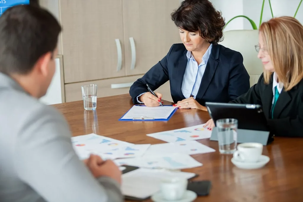 Profesionales reunidos con clientes revisando documentos importantes en un entorno formal de traducciones legales y jurídicas